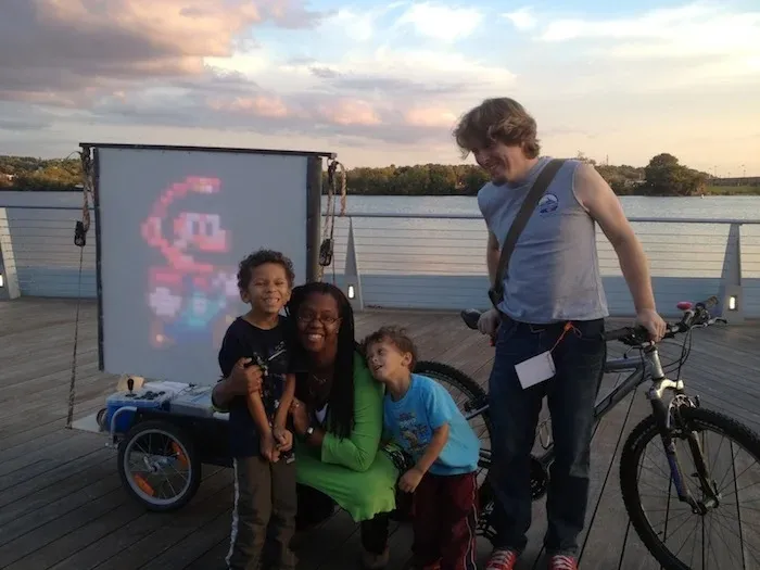 Branden posing with his family in front of his Blitter Bike art project