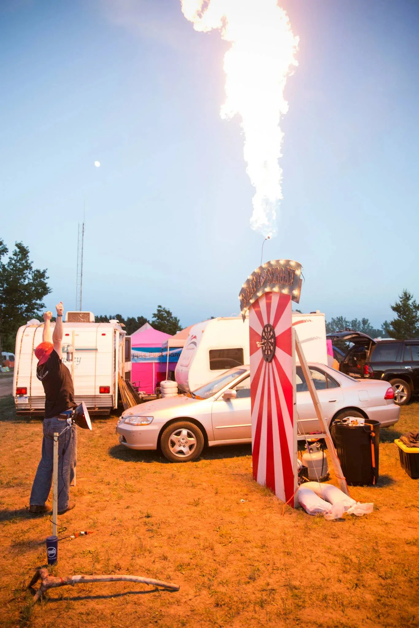 Man with raised hands standing in front of a dart board shooting fire